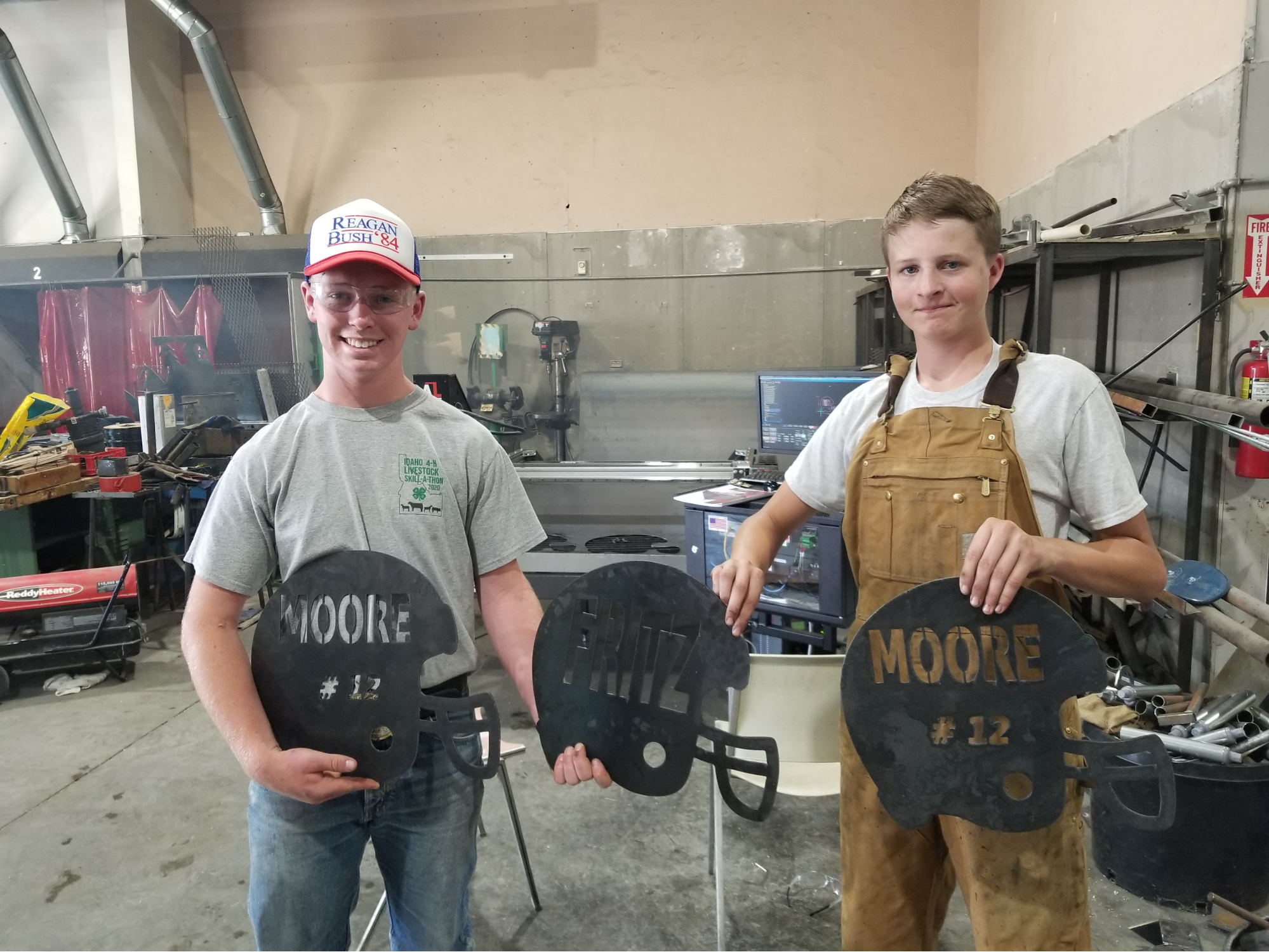 Two students holding items they cut during Metal Fabrication class.